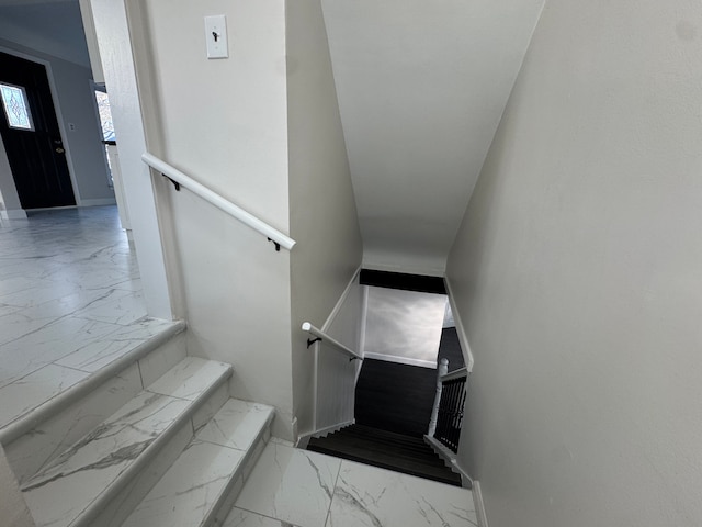 stairway featuring marble finish floor and baseboards