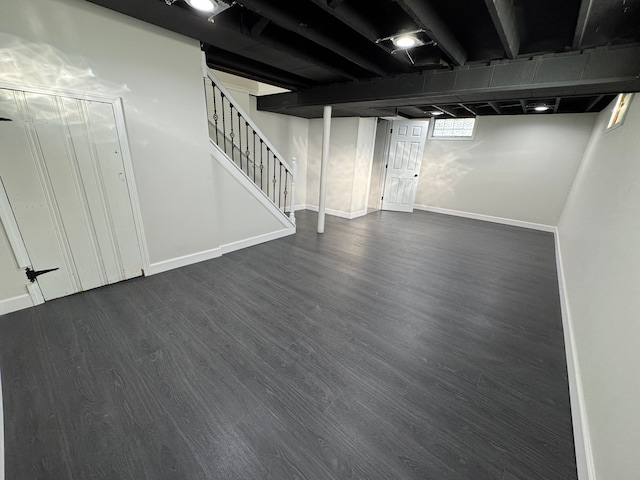 basement with baseboards, stairway, and dark wood finished floors