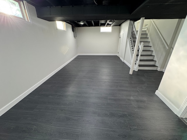 basement with dark wood-type flooring, a wealth of natural light, and baseboards