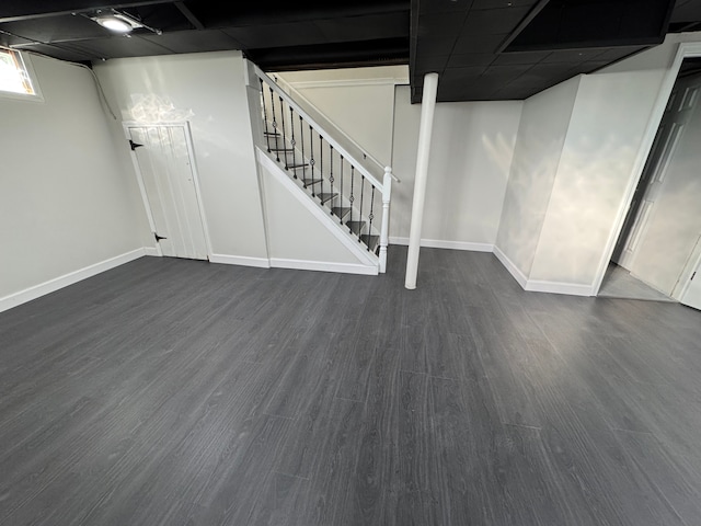 basement with stairs, dark wood-type flooring, and baseboards