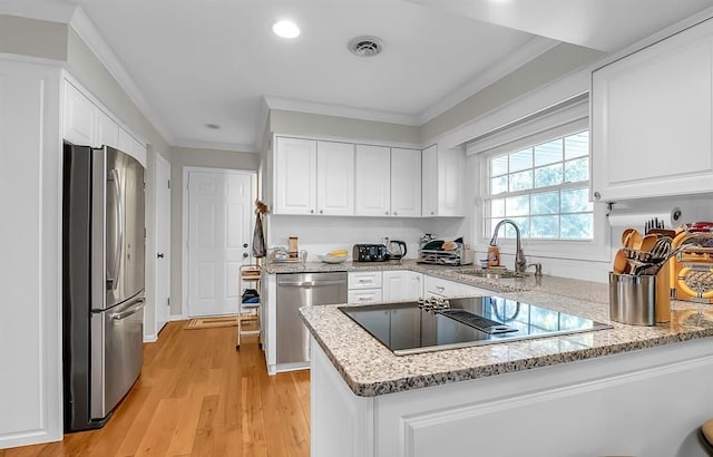 kitchen with a sink, visible vents, white cabinetry, ornamental molding, and appliances with stainless steel finishes