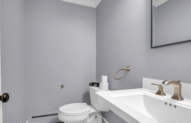 half bath featuring a baseboard radiator, a sink, and toilet