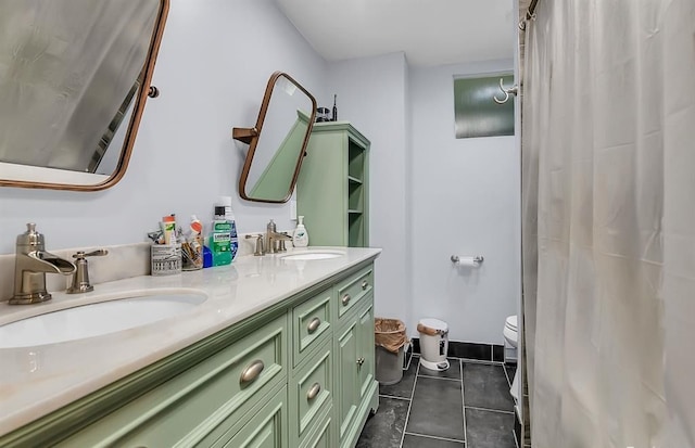 bathroom with toilet, double vanity, a sink, and tile patterned floors