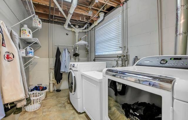 laundry room featuring laundry area, concrete block wall, and washer and dryer