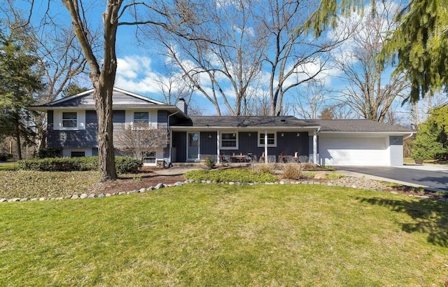 tri-level home featuring an attached garage, driveway, a chimney, and a front yard