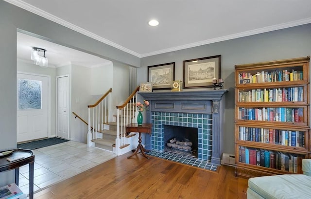 interior space with crown molding, stairs, a baseboard heating unit, and wood finished floors