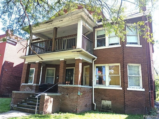 view of front of property with brick siding, a porch, and a balcony