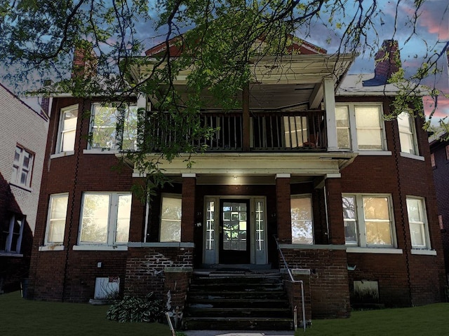 view of property featuring brick siding and a balcony