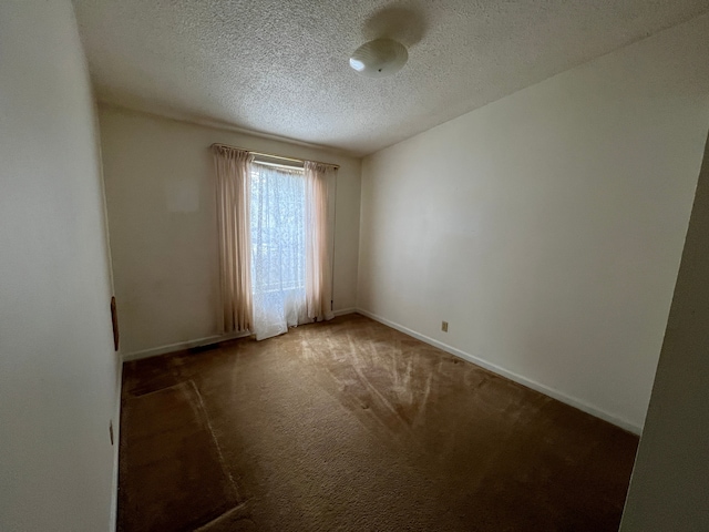 empty room with carpet, a textured ceiling, and baseboards