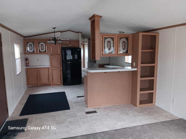 kitchen featuring freestanding refrigerator, a peninsula, light countertops, vaulted ceiling, and a textured ceiling