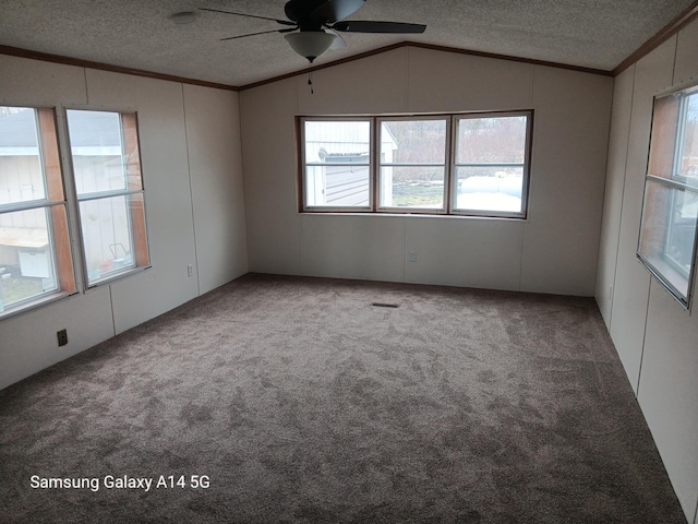 carpeted spare room with ornamental molding, vaulted ceiling, a textured ceiling, and ceiling fan