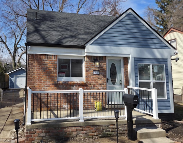 view of front of house featuring a porch, concrete driveway, brick siding, and roof with shingles