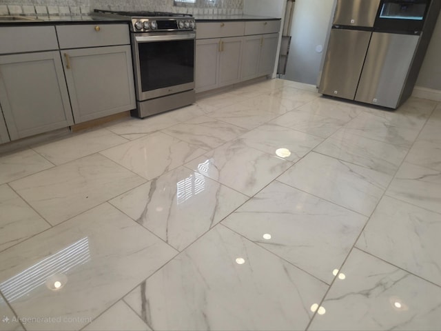 kitchen with dark countertops, appliances with stainless steel finishes, marble finish floor, gray cabinetry, and a sink