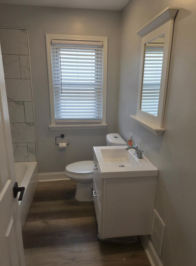 full bathroom featuring toilet, a wealth of natural light, visible vents, and wood finished floors