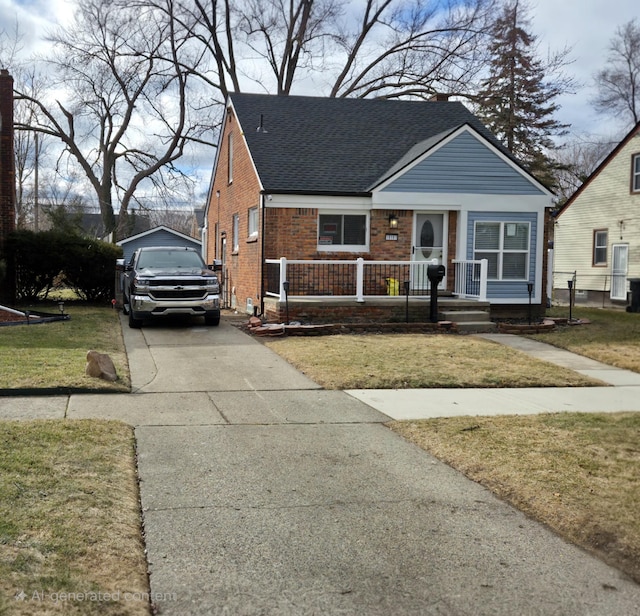 bungalow with a porch, a front yard, concrete driveway, and brick siding