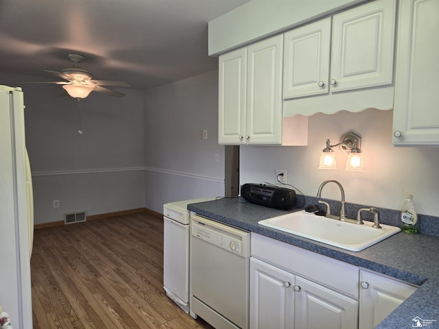 kitchen featuring white appliances, a sink, visible vents, white cabinets, and dark wood finished floors