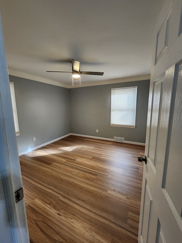 spare room featuring ceiling fan, wood finished floors, visible vents, and baseboards