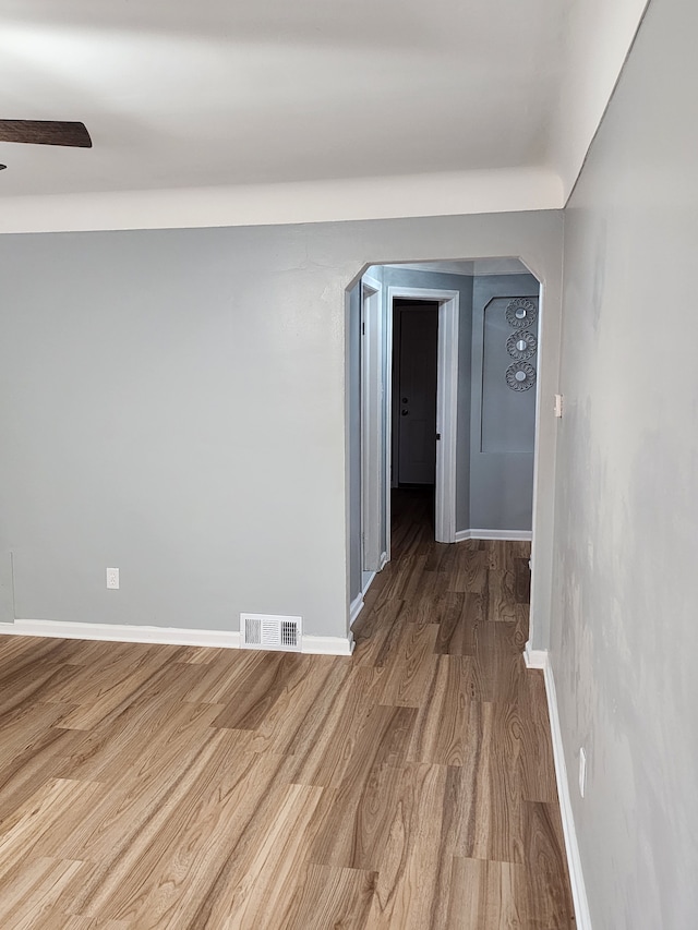 empty room with visible vents, baseboards, wood finished floors, and a ceiling fan