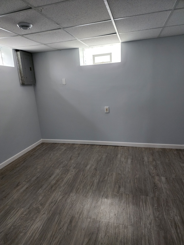 basement with a paneled ceiling, baseboards, and wood finished floors