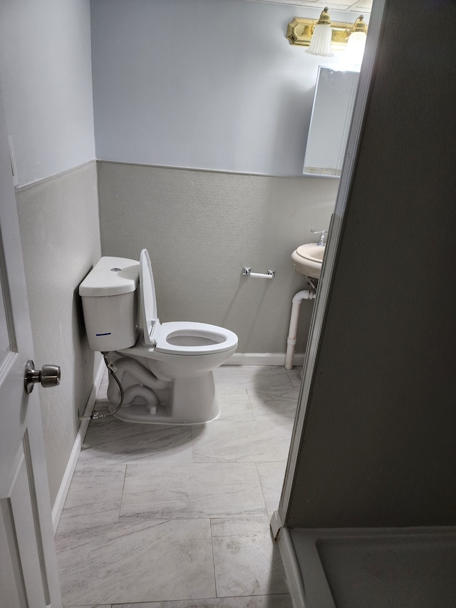 bathroom featuring toilet, baseboards, and marble finish floor