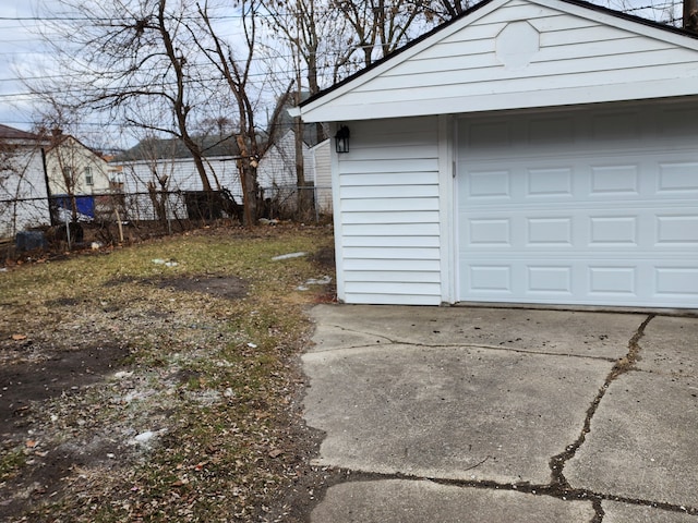 garage featuring concrete driveway and fence