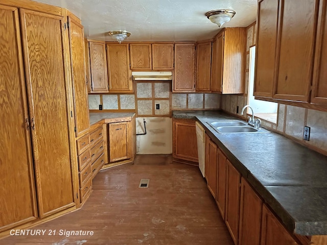 kitchen with visible vents, brown cabinets, wood finished floors, under cabinet range hood, and a sink