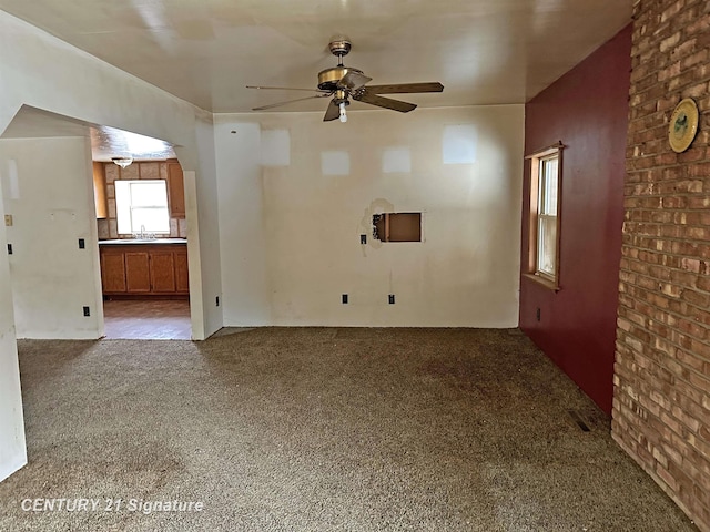 unfurnished living room featuring carpet, a sink, and a ceiling fan