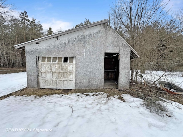 snow covered garage with a detached garage