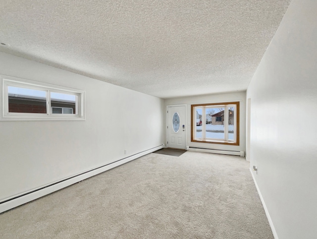 carpeted spare room with a baseboard radiator, a textured ceiling, a baseboard heating unit, and baseboards