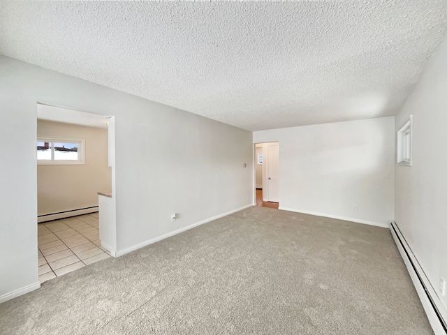 carpeted spare room featuring baseboard heating, a textured ceiling, and tile patterned floors