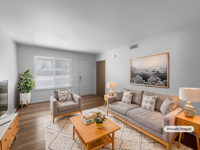 living area with baseboards, visible vents, and wood finished floors