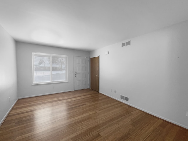 empty room featuring baseboards, visible vents, and wood finished floors