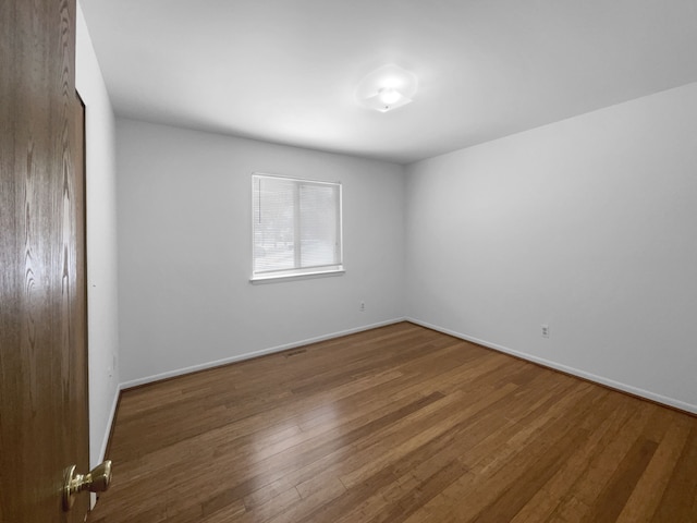 empty room featuring baseboards and hardwood / wood-style flooring