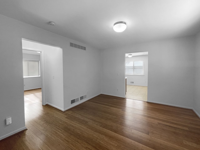 unfurnished room featuring visible vents, baseboards, and hardwood / wood-style flooring