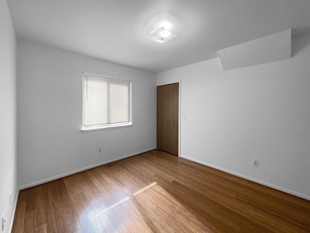 empty room featuring hardwood / wood-style flooring and baseboards