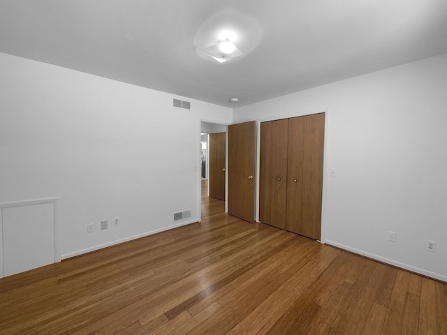 unfurnished bedroom with wood finished floors, visible vents, and baseboards