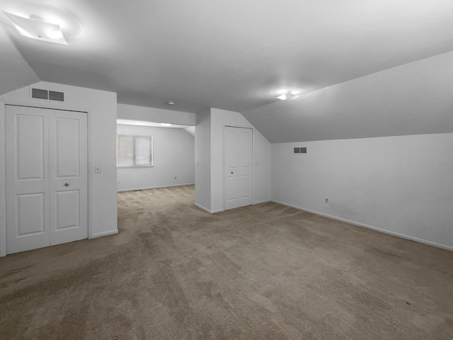 bonus room featuring carpet floors, visible vents, vaulted ceiling, and baseboards