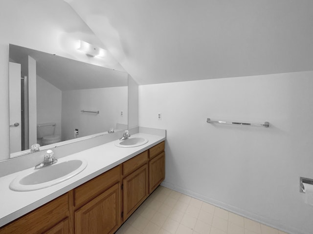 full bath with toilet, double vanity, a sink, and lofted ceiling