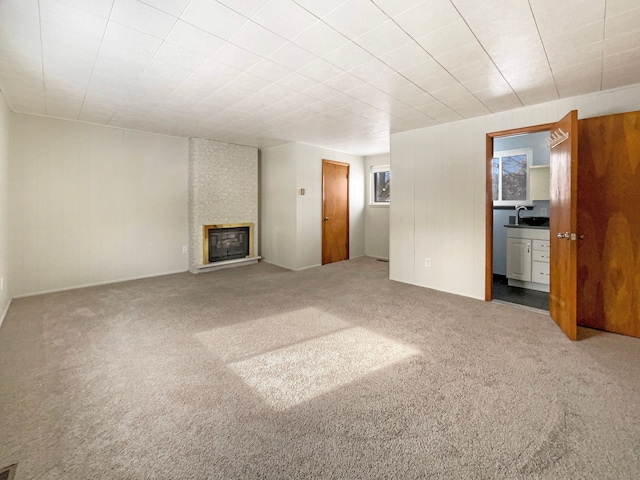 unfurnished living room with carpet, a large fireplace, and a sink