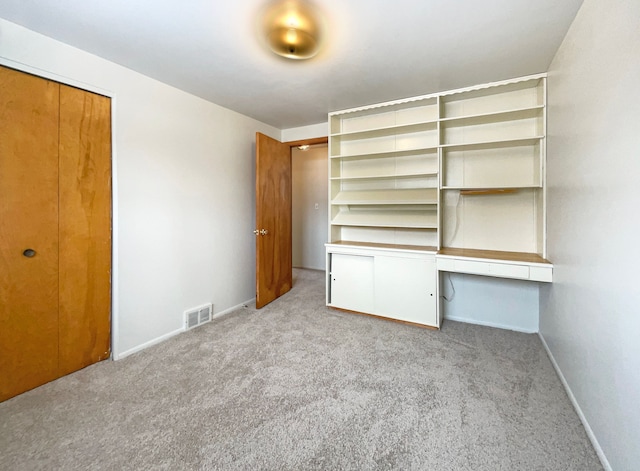 unfurnished bedroom with light carpet, baseboards, visible vents, and built in study area