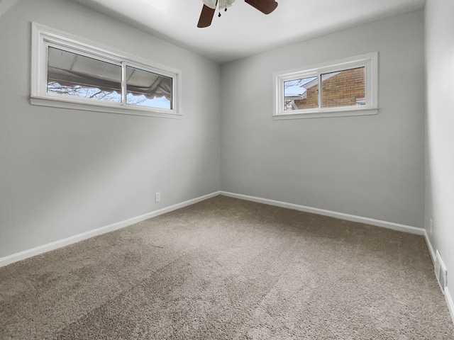 carpeted empty room with visible vents, ceiling fan, and baseboards