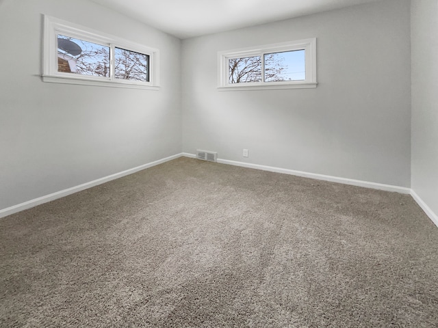 spare room featuring plenty of natural light, visible vents, baseboards, and carpet flooring