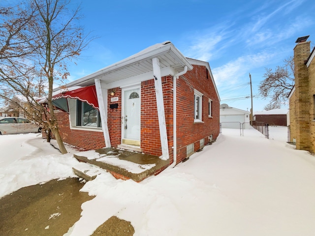 view of front of house featuring a gate, brick siding, an outdoor structure, and a detached garage