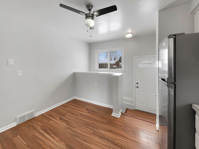 unfurnished dining area with ceiling fan, wood finished floors, visible vents, and baseboards