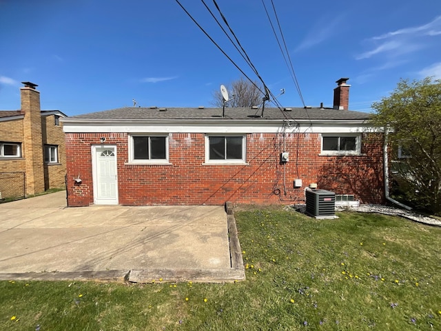 back of house featuring a patio, central AC unit, brick siding, a lawn, and a chimney