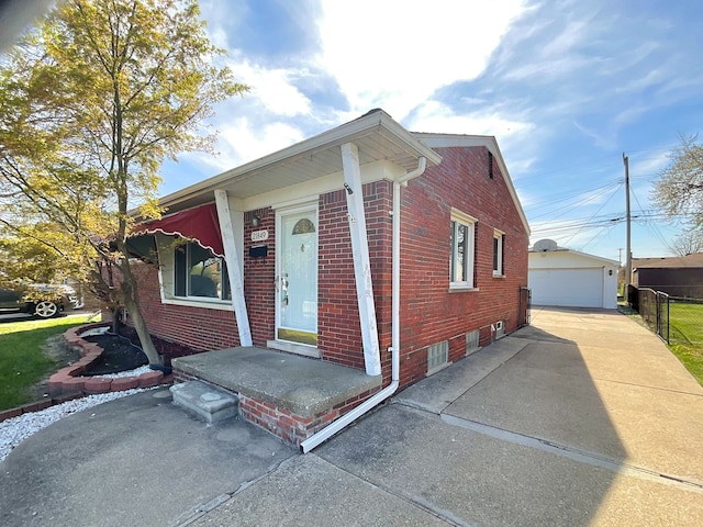 view of front of house featuring fence, an outdoor structure, a detached garage, and brick siding