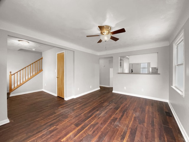 unfurnished living room with stairs, ceiling fan, dark wood-style flooring, and baseboards