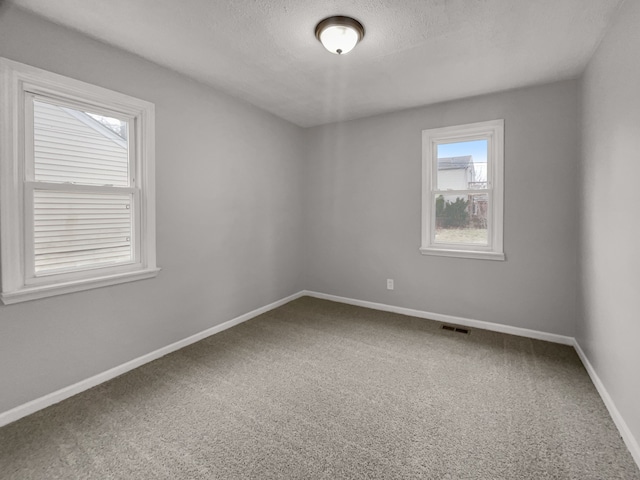 empty room featuring a textured ceiling, carpet flooring, and baseboards