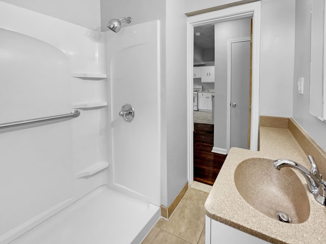 bathroom with a shower, tile patterned flooring, vanity, and baseboards