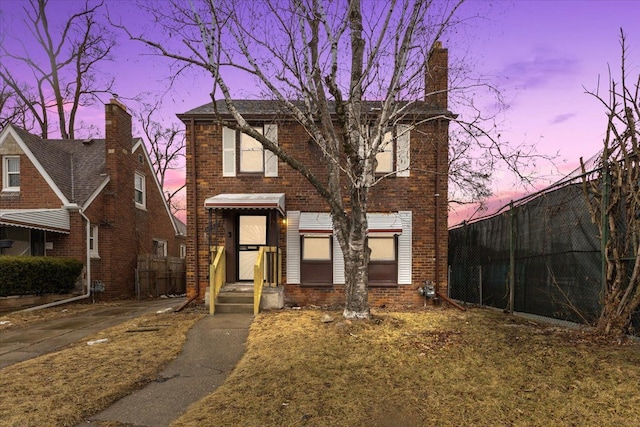 view of front facade featuring brick siding and fence